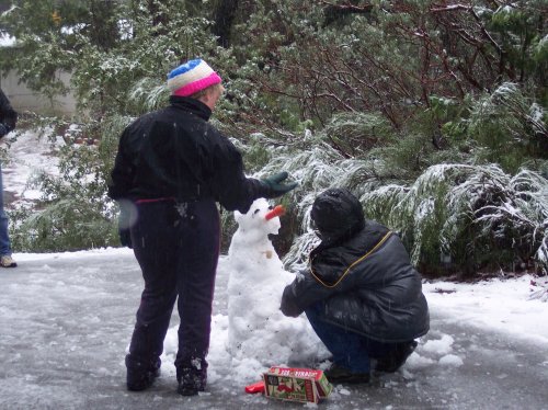 Melissa and Jonny putting face on snowman 