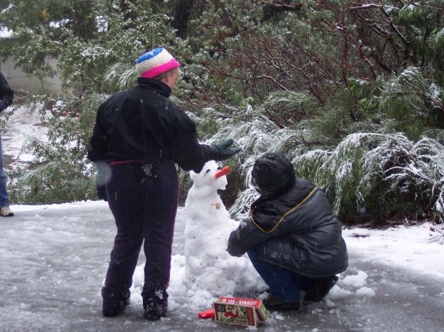 Melissa and Jonny putting face on snowman 